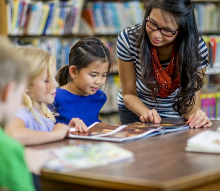 Lady teaching children in a library
